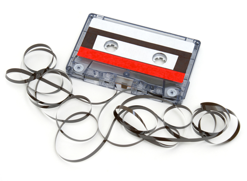 A cassette tape has been destroyed and the tape unraveled.