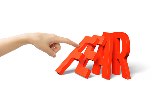 Woman finger pushing domino of red fear word falling, isolated on white.